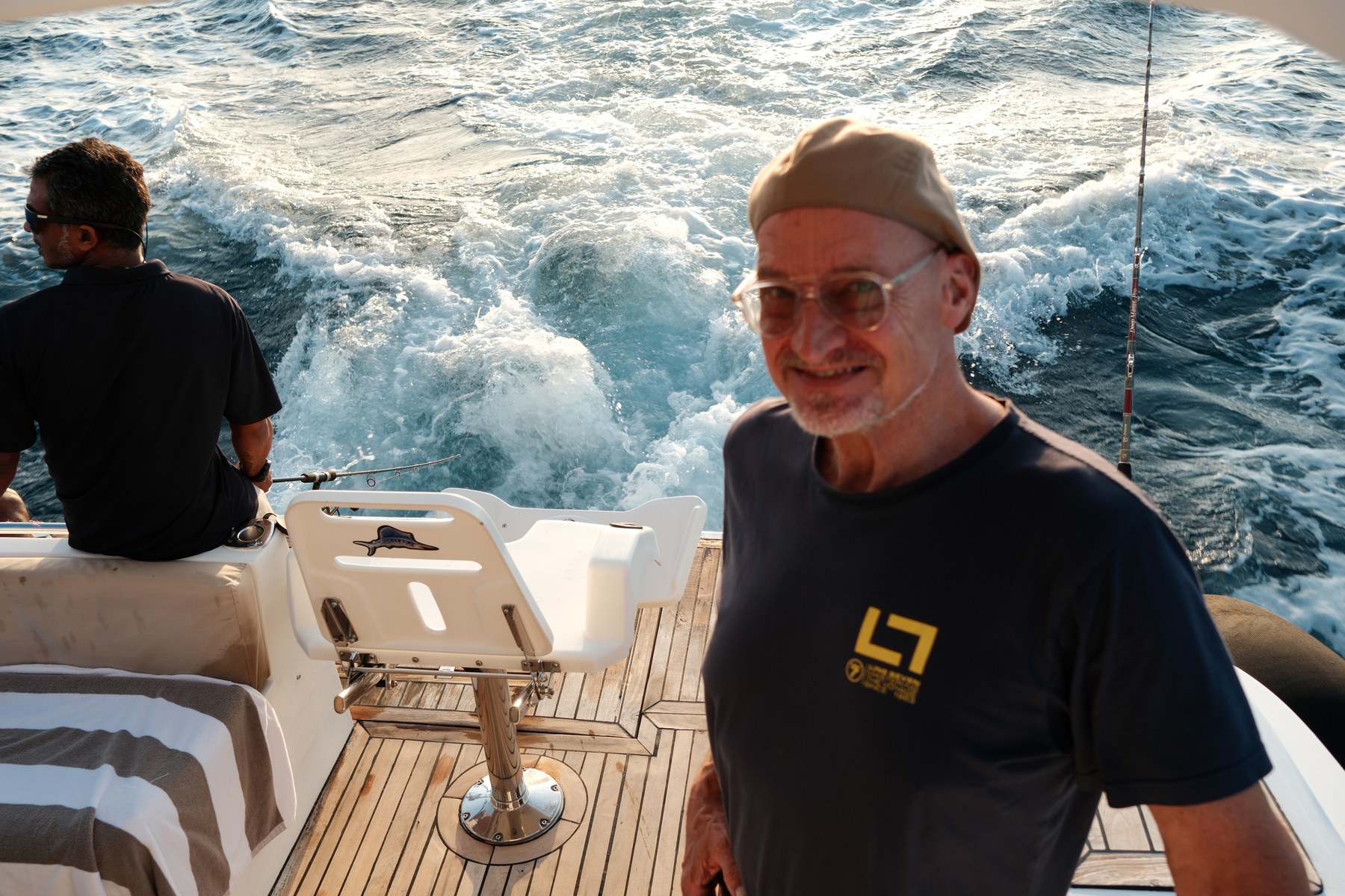 Michael on the back of a boat at sea, turning to smile at the camera.