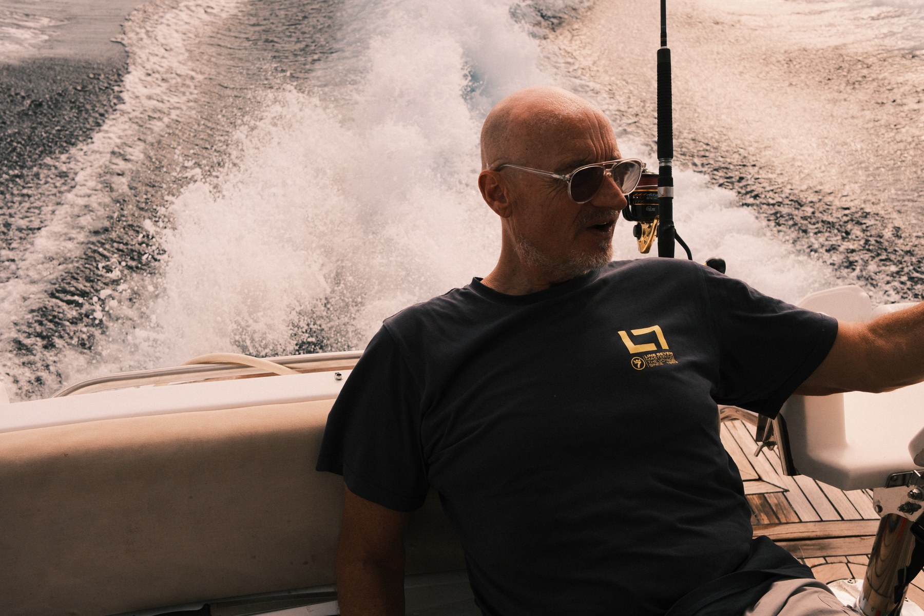 Michael seated at the stern with the wake behind him and a rod in the holder.